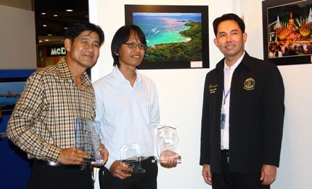 Mayor Itthiphol Kunplome and Sawat Pattiphanprasert, president of the Federation of Photographic Associations of Thailand, congratulate Sanchai Lungrung, who’s photo “Sawan Tawanork” (background) won Pattaya’s second-annual photo contest.